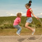 Дети прыгают на скакалке в поле