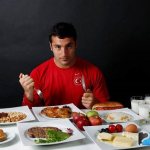 Спортсмен за столом готовится есть